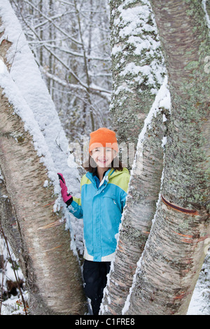 Gemischte Rassen Mädchen stehen auf schneebedeckten Baum Stockfoto