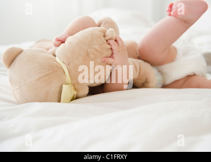 Gemischte Rassen Baby auf Bett mit Teddybär Stockfoto