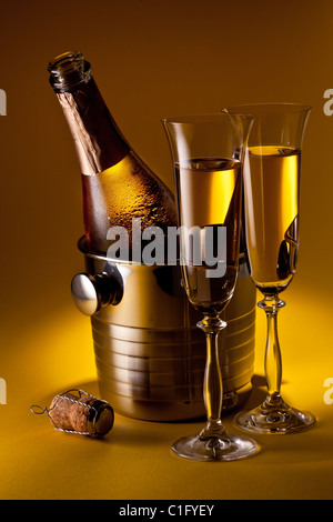 Flasche Champagner im Kühler und zwei Sektgläsern. Auf einem gelben isoliert. Stockfoto