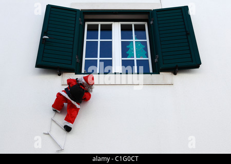 Santa Claus Figur klettert eine Leiter zum Fenster einer Wohnung in Lissabon, Portugal. Stockfoto