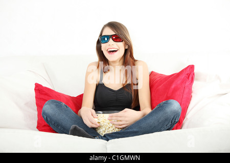 Schöne junge Frau vor dem Fernseher in 3d Brille und Essen popcorn Stockfoto