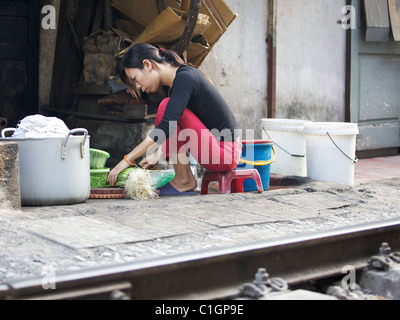 Die Lebensdauer der Bahnstrecke im Herzen von Hanoi, Vietnam. Eine Frau bereitet das Abendessen. Stockfoto