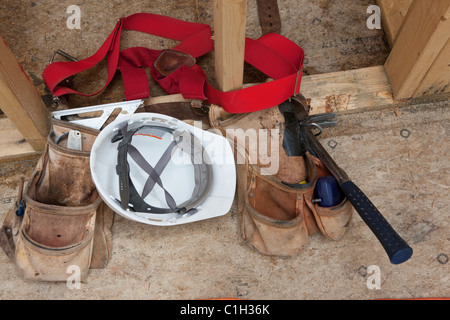 Werkzeuggürtel mit Werkzeugen und einem Schutzhelm auf einer Baustelle in Nahaufnahme Stockfoto