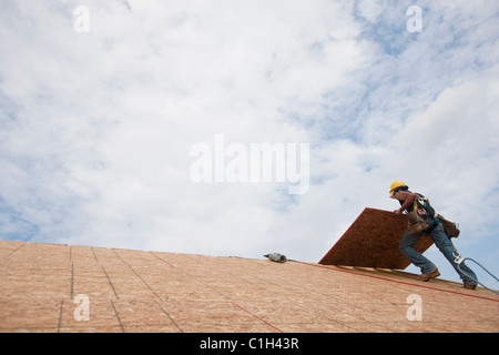Niedrigen Winkel Blick auf Aufhebung einer Dachplatte auf dem Dach eines Hauses im Bau Schreiner Stockfoto