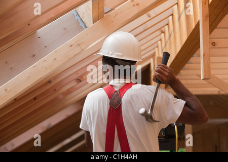 Hispanische Zimmermann mit Hammer im Obergeschoss in einem Haus im Bau Stockfoto