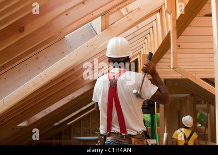Hispanische Zimmermann mit Hammer im Obergeschoss in einem Haus im Bau Stockfoto