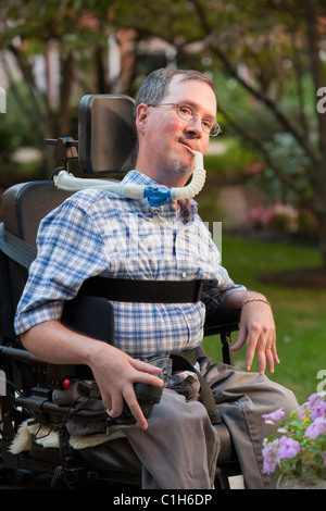 Mann mit Duchenne-Muskeldystrophie sitzt in einem Rollstuhl mit einem Atem-ventilator Stockfoto