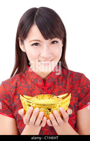 Schöne asiatische Frau tragen Cheongsam und halten chinesische Goldbarren Stockfoto