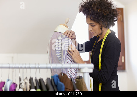 Junge weibliche hispanische Schneiderin anpassen Kleidung auf Schneiderei Mannequin. Horizontale Form, Hüfte aufwärts Textfreiraum Stockfoto