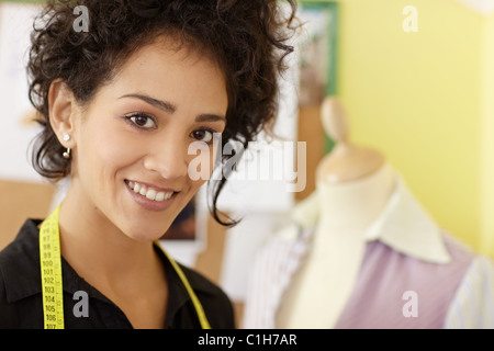 Portrait of young hispanic female dressmaker with mannequin in background. Horizontal shape, head and shoulders, copy space Stockfoto