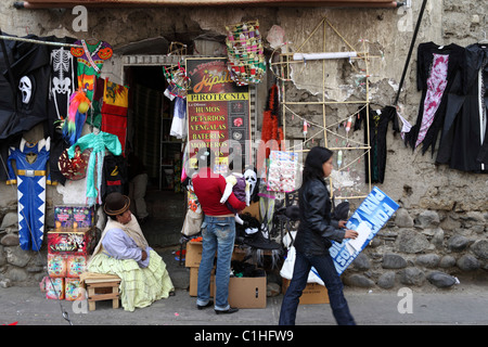 Aymara-Frau, die vor dem Eingang des Ladens sitzt und Feuerwerksmasken und Kostüme für Halloween, La Paz, Bolivien verkauft Stockfoto