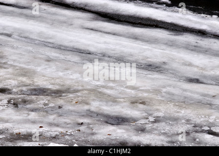 Pkw-Reifen tritt auf tief verschneiten Straße mit dreckigen nassen Schneematsch und Eis Stockfoto