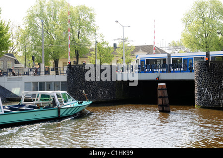 Boot geht unter die Kanalbrücke während Straßenbahn drüber Stockfoto