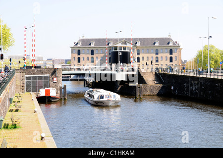 Tourenboot geht unter einer Kanalbrücke in Amsterdam Stockfoto
