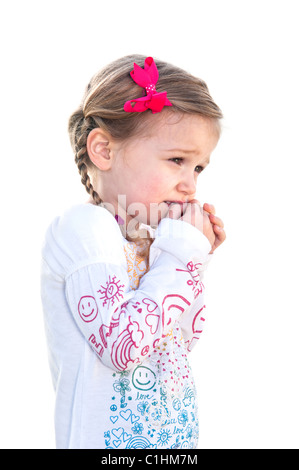 Ein wunderschönes kleines Mädchen auf einem weißen Hintergrund ist erschrocken und hält ihre Hand auf ihr Gesicht. Stockfoto