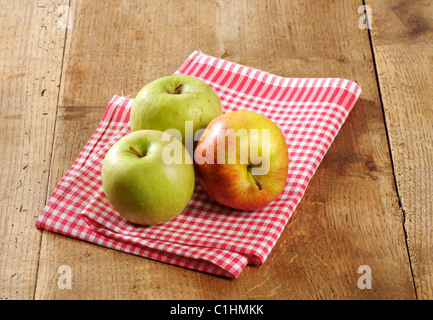 Drei frische Äpfel auf einem rustikalen Tisch Stockfoto