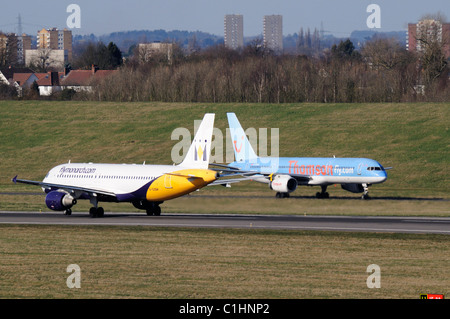 Ein Monarch Airlines Airbus A320 fährt vorbei an einer Thomson Boeing 757, die gerade am Birmingham International Airport angekommen ist. Stockfoto