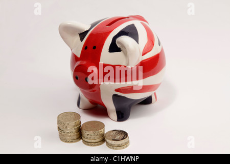 Schwein Spardose mit einem britischen "Union Jack" Flagge gemalt und einige britische ein Pfund-Münzen vor es platziert. Stockfoto