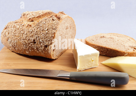 Frisch geschnitzte Getreidespeicher Walnuss-Brot mit zwei Käse Keile auf eine blasse Blaue Tischdecke gelegt. Stockfoto