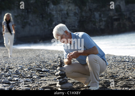 Senior woman Stapeln Steinen am Strand, Italien Stockfoto