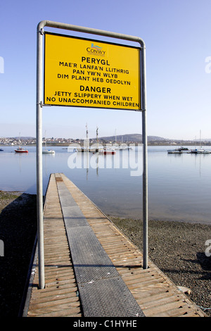 Ein Warnsignal in Walisisch und Englisch auf einem Steg im Hafen von Conwy, Nordwales Stockfoto