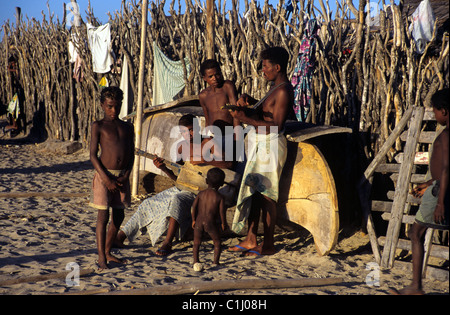 Vezo Fishermen, Musiker, Männer und Jungen Spielen Gitarre, während Leaning auf Dem Umgestuften Kanu am Strand von Anakao, in der Nähe von Tulear oder Toliara Madagaskar Stockfoto