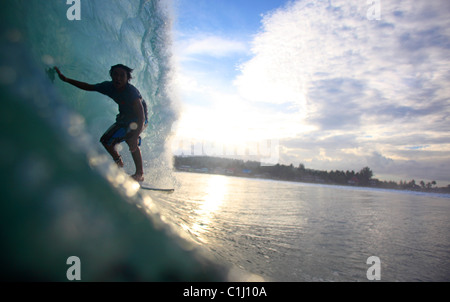 Lokalen Surfer reitet ein Fass Lagundri Bay in der Abenddämmerung auf der Insel Nias, Sumatra, Indonesien Stockfoto