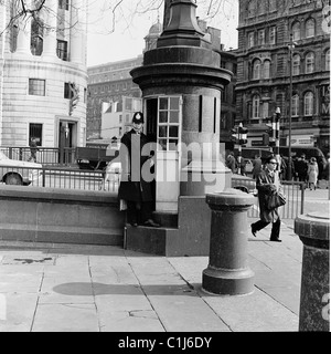 1960er Jahre, ein britischer Polizist, der an der ein-Mann-Polizeibox am Trafalgar Square, Westminster, London, der kleinsten Polizeistation Großbritanniens, steht. Stockfoto