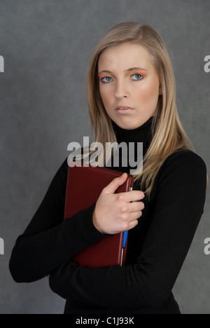 Bildnis einer blonden Frau in ein schwarzes t-Shirt mit einem roten Notebook auf grauem Hintergrund Stockfoto