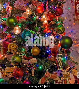 Dieser Weihnachtsbaum ist stark mit vielen verschiedenen farbigen Ornament Kugeln und Lichtern geschmückt. Stockfoto