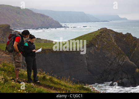 Wanderer, die Blick auf einen Reiseführer auf der Klippe am Hartland Quay (Teil des South West Coast Path), Devon, England Stockfoto