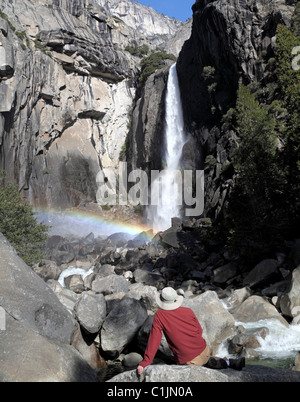 Mann sitzt auf Boulder bewundert unteren Yosemite Fall Stockfoto