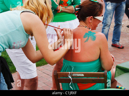 Frau, die Kleeblätter gemalt auf Rückseite am St. Patricks Tag vor irischen Bar in Spanien Stockfoto