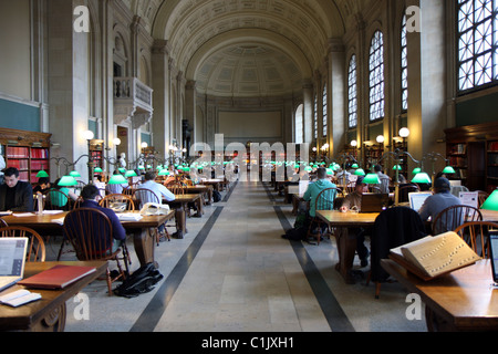 Innenraum der Public Library in Boston und ein Schüler lesen Bücher unter grünen Lampen im Hauptlesesaal Stockfoto