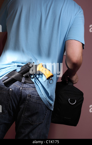 Mann mit Pistole versteckt im Raum mit schwarzen Tasche Gürtel Stockfoto