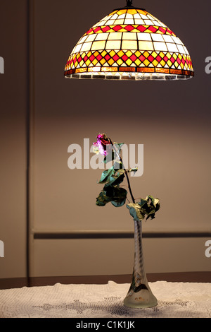 Eine getrocknete Rose in Glasvase unter Pendelleuchte Stockfoto