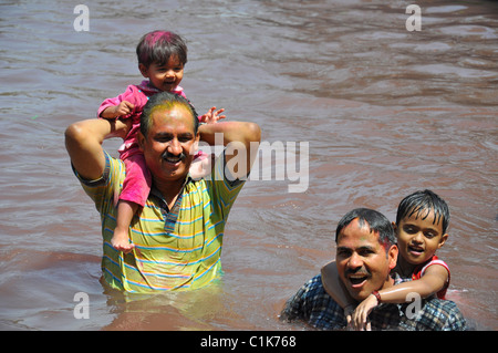 Zwei indianer mit Kindern im Wasser spielen Holi Stockfoto