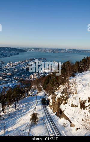 Blick auf den Hafen von Bergen an einem Wintertag. Im Vordergrund sehen Sie eine Seilbahn, die zu einem Aussichtspunkt über die Stadt geht. Stockfoto