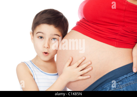 Überrascht junge Mutter Bauch mit Händen halten und hören auf weißem Hintergrund Stockfoto
