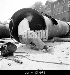 1950er Jahre London. In dieses Geschichtsbild durch J Allan Cash sitzt ein männliche Arbeiter in einem großen runden Rohr auf einer Baustelle. Stockfoto