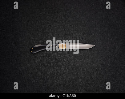 Klappbare Stift Messer Still-Leben auf einem Hintergrund aus schwarzem Leder Stockfoto