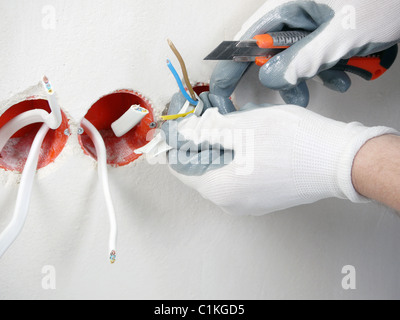 Nahaufnahme des Elektrikers Hände Abisolieren von elektrischen Kabeln für Steckdose Stockfoto