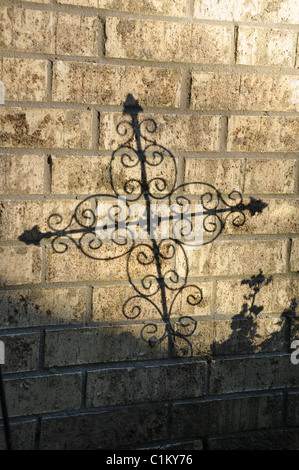 Schatten einer Schriftrolle Kreuz auf einer weißen Mauer im Sonnenlicht Stockfoto