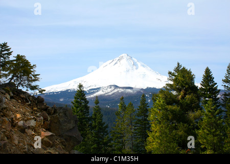 40,257.07614 einer fernen schneebedeckten Berg - Mt Hood (11,240 ft hoch) - Gipfel über einen Baum bedeckten felsigen Grat oben, gegen ein weiches blauen Himmel. Stockfoto