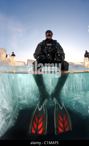 Split Level, sitzt männliche Eis-Taucher auf dem Eis in den Baikalsee, Sibirien, Russland, Insel Olchon. Stockfoto