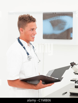Lächelnd jungen Arzt mit Phonendoscope mit guten Nachrichten über Diagnose; Stockfoto