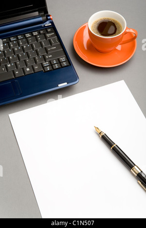 Bild von leeren Papierbogen, Füllfederhalter und PocketPC am Arbeitsplatz mit Tasse Kaffee in der Nähe von Stockfoto