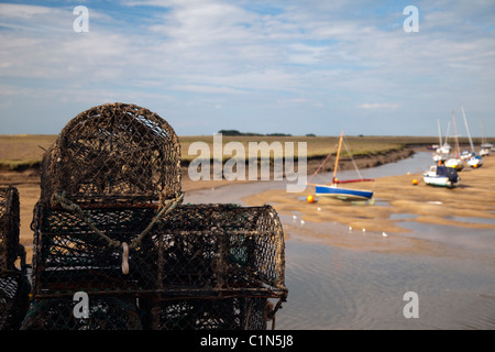 Krabbe Töpfe/Körbe gestapelt auf Kai mit Segelbooten in der Ferne Brunnen als nächstes Meer Norfolk East Anglia England Stockfoto