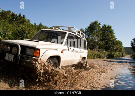 Ein Allradfahrzeug macht seinen Weg auf eine Straße zu einem der vielen Seen außerhalb Yuzhno Sakhalinsk, Sachalin, Russland Stockfoto