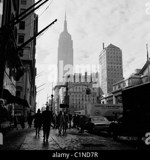 1950 s, historischen, einer geschäftigen Stadt New York Street, mit dem Art Deco skyscrapper, das Empire State Building in Midtown Manhattan, im Hintergrund. Stockfoto